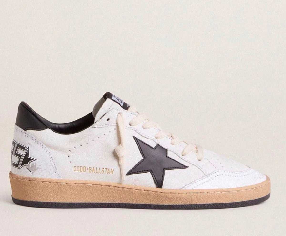 White sneaker with black star and sole on a light gray background