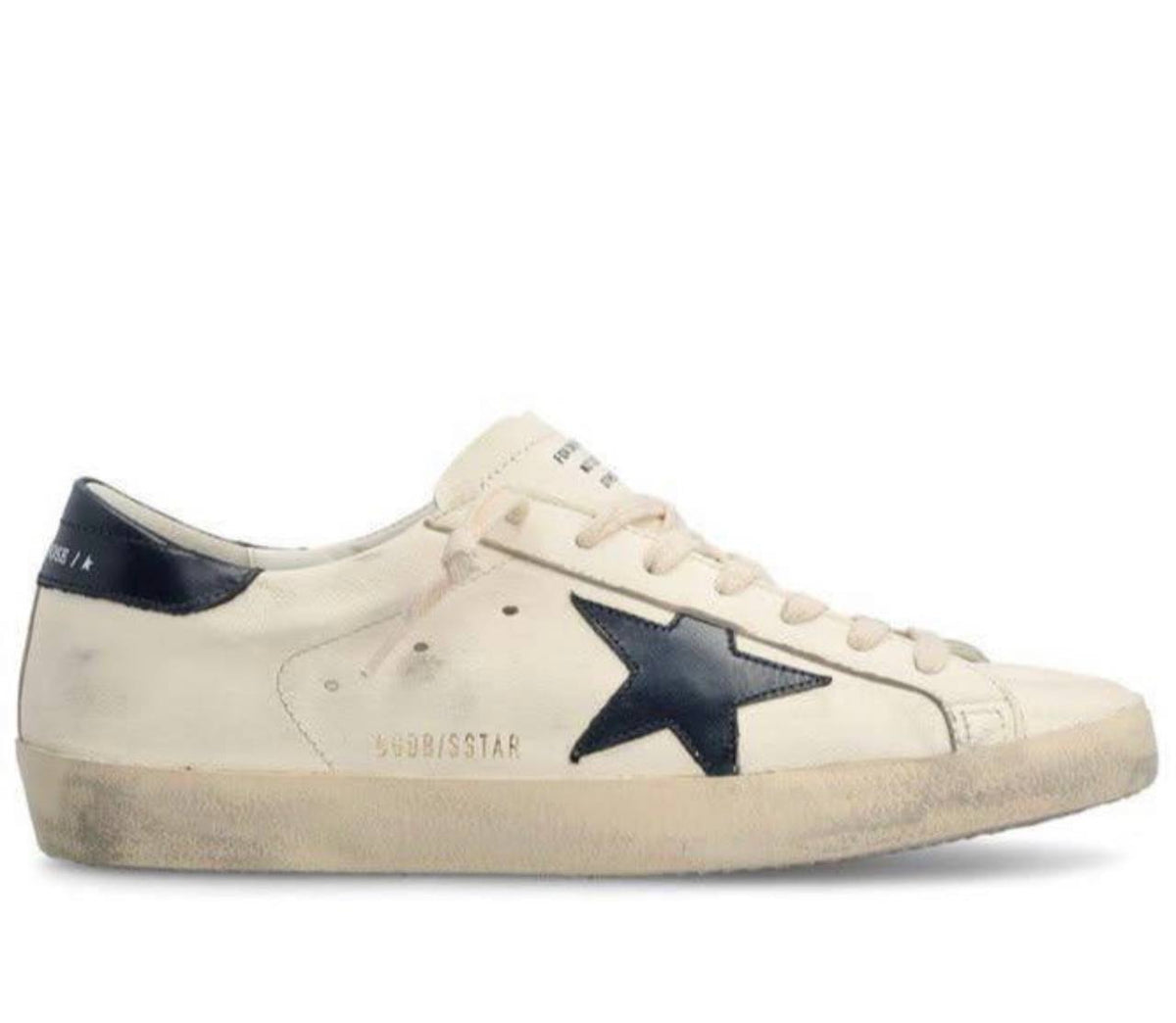 A Golden Goose Super-Star sneaker in distressed off-white leather with a dark navy blue star on the side and a navy heel tab, shown against a plain white background.